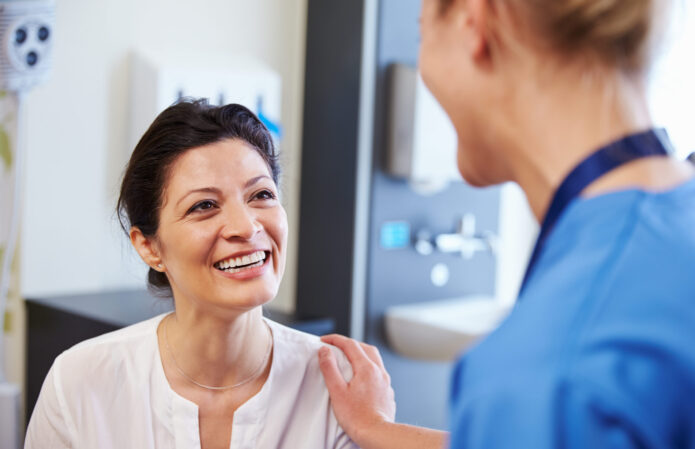 Female Patient Being Reassured By Doctor In Hospital Room - Image